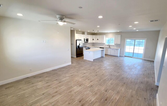 kitchen featuring open floor plan, light countertops, a sink, visible vents, and appliances with stainless steel finishes