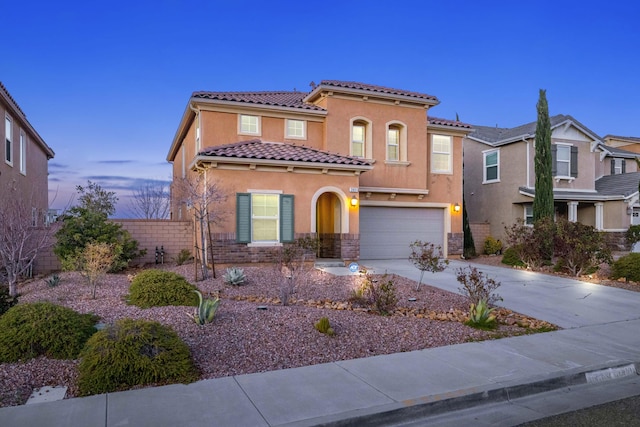 mediterranean / spanish house featuring fence, driveway, an attached garage, stucco siding, and a tile roof