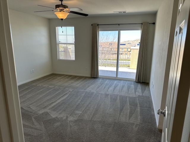 carpeted empty room featuring visible vents, baseboards, and ceiling fan