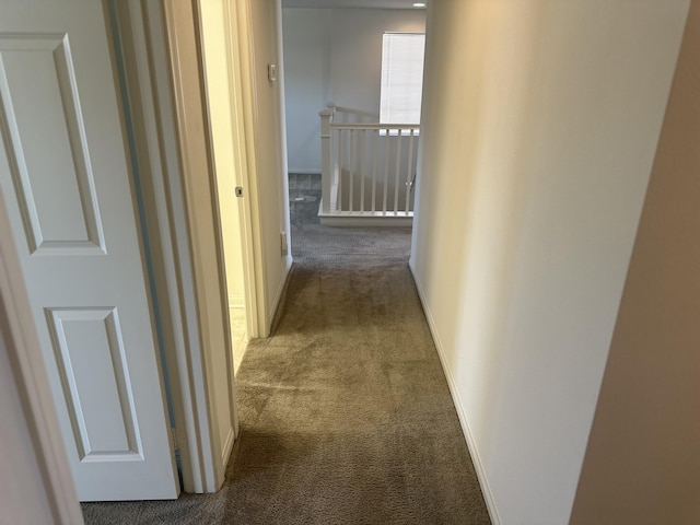 hall with an upstairs landing, baseboards, and carpet floors