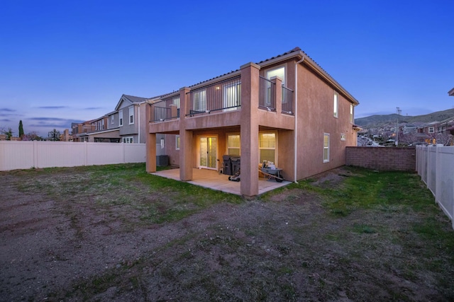 rear view of property with a yard, a patio area, a fenced backyard, and stucco siding