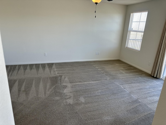 carpeted empty room featuring baseboards and ceiling fan