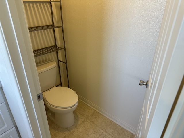 bathroom featuring tile patterned flooring, toilet, and baseboards