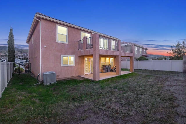 back of house with a fenced backyard, central AC, stucco siding, a patio area, and a lawn