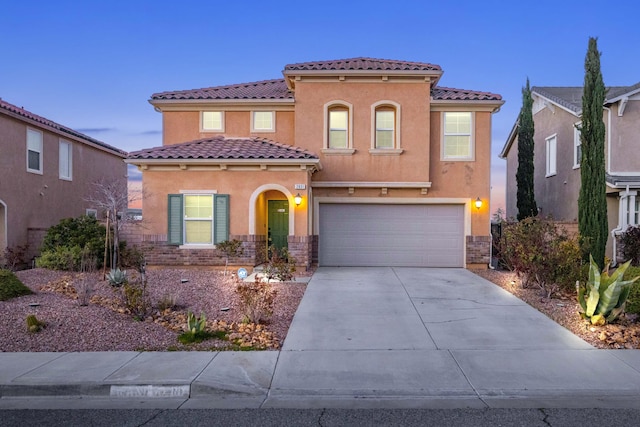 mediterranean / spanish-style home featuring stucco siding, a garage, driveway, and a tiled roof