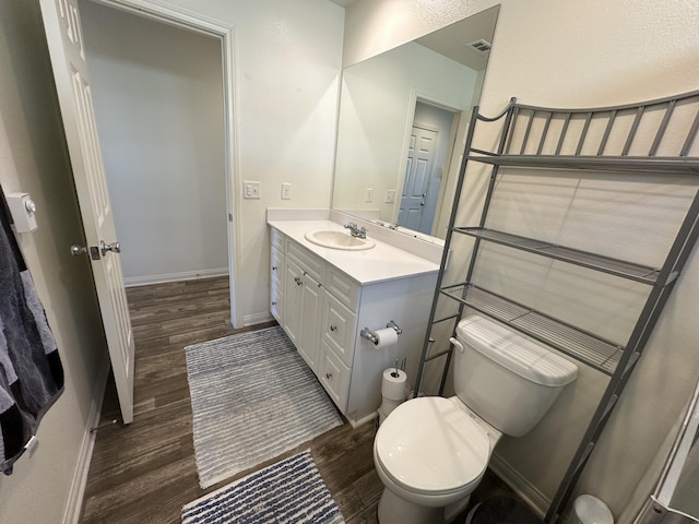 bathroom featuring baseboards, toilet, wood finished floors, and vanity