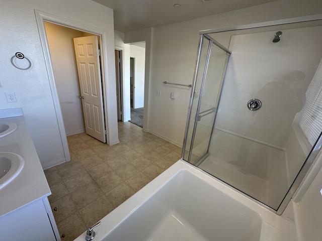 full bathroom featuring double vanity, a stall shower, baseboards, and a sink