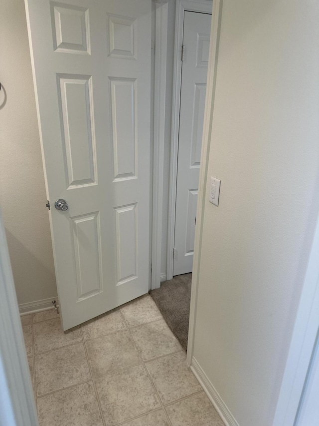 hall featuring light tile patterned floors and baseboards