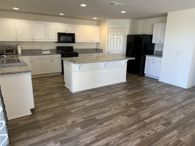 kitchen featuring white cabinetry, black appliances, visible vents, and a sink