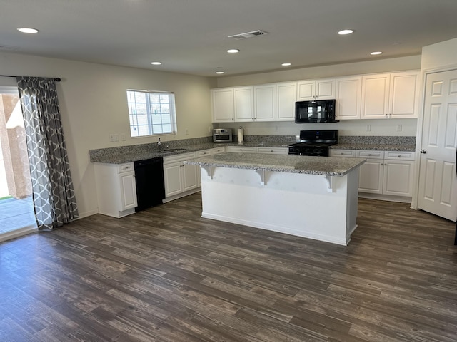 kitchen featuring visible vents, black appliances, white cabinets, dark wood-type flooring, and a center island