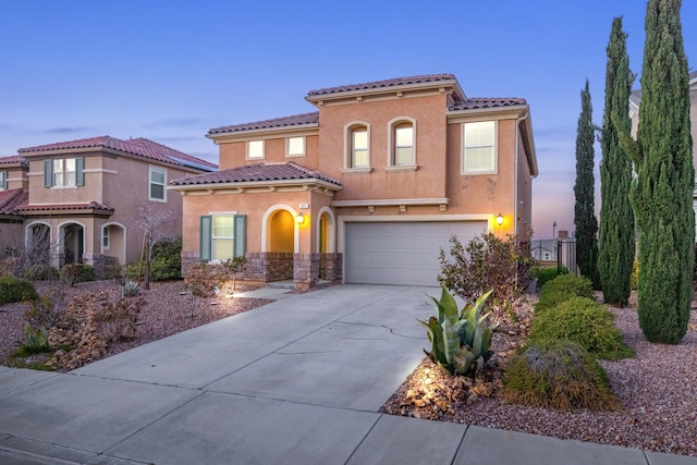 mediterranean / spanish-style house with stucco siding, concrete driveway, an attached garage, and a tiled roof