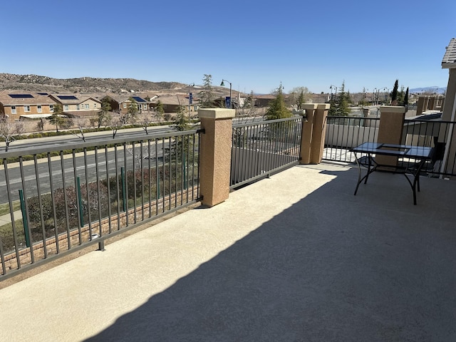 view of patio with a mountain view, a residential view, and a balcony