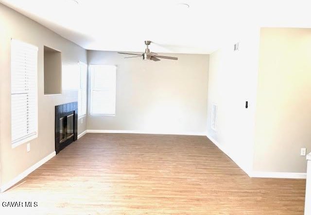 3503 Glenridge Ave, Rosamond, CA 93560 - unfurnished living room with a ceiling fan, light wood-style floors, and a glass covered fireplace