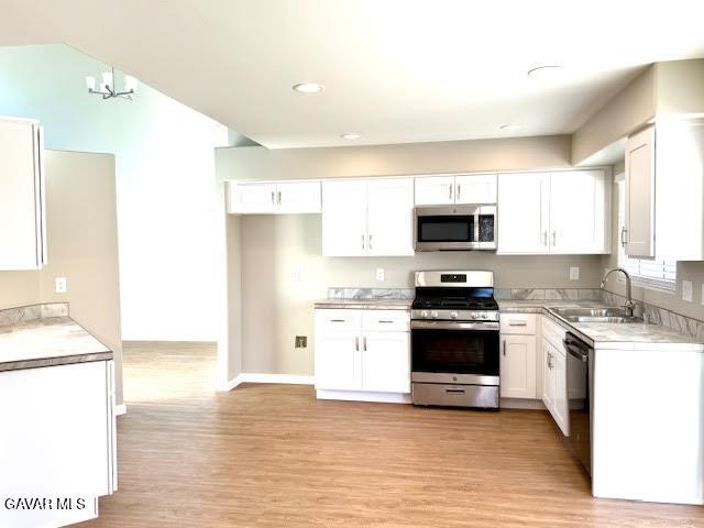 3503 Glenridge Ave, Rosamond, CA 93560 - kitchen featuring appliances with stainless steel finishes, white cabinets, light countertops, light wood finished floors, and recessed lighting