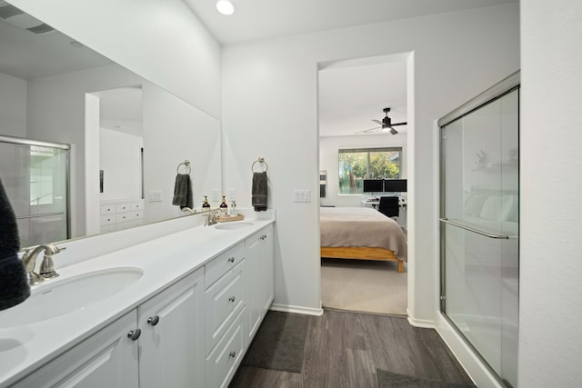 ensuite bathroom featuring ensuite bathroom, wood finished floors, a stall shower, and a sink