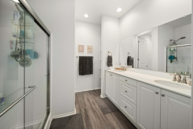 full bath with wood finished floors, a sink, a shower stall, and double vanity