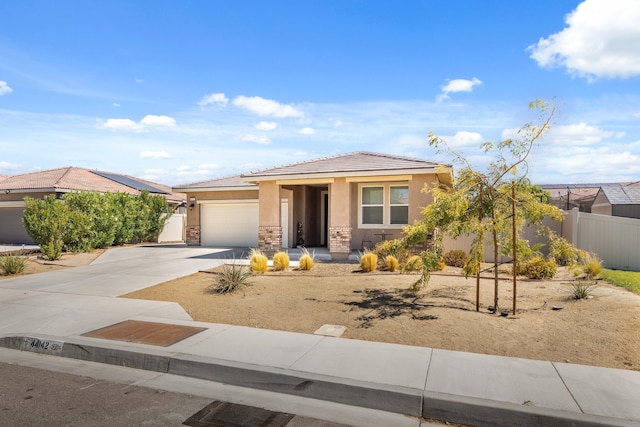 prairie-style home with a garage, fence, driveway, stone siding, and stucco siding