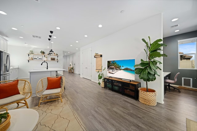 living room with light wood-type flooring, visible vents, baseboards, and recessed lighting