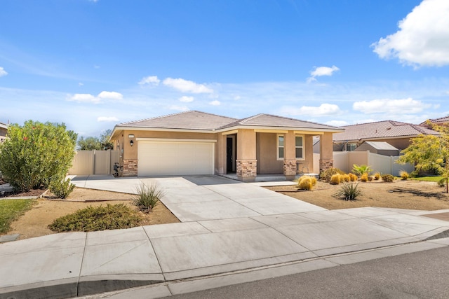 prairie-style home featuring a garage, fence, stone siding, concrete driveway, and stucco siding