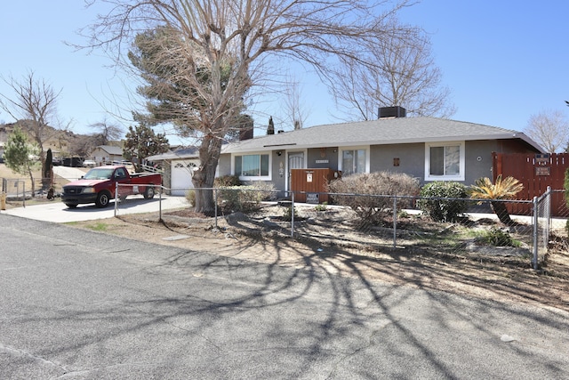 ranch-style home with concrete driveway, a fenced front yard, and an attached garage