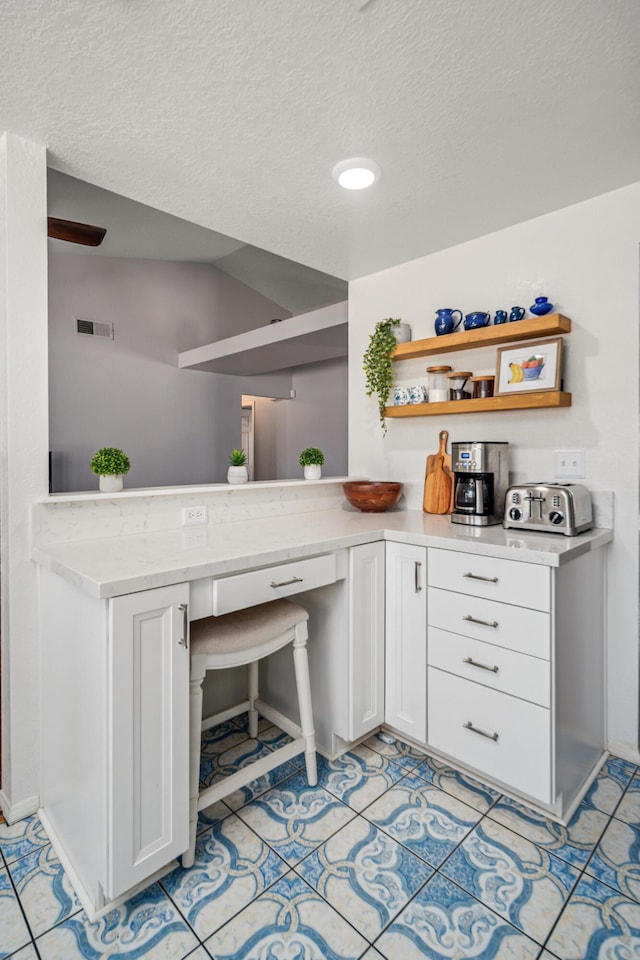 bar featuring white cabinetry, light tile patterned floors, and a textured ceiling