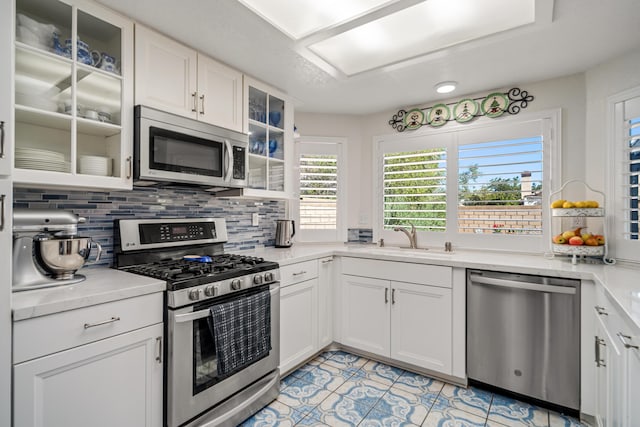 kitchen featuring white cabinets, appliances with stainless steel finishes, backsplash, and sink