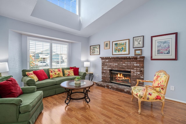 living room featuring a high ceiling, light hardwood / wood-style floors, and a brick fireplace