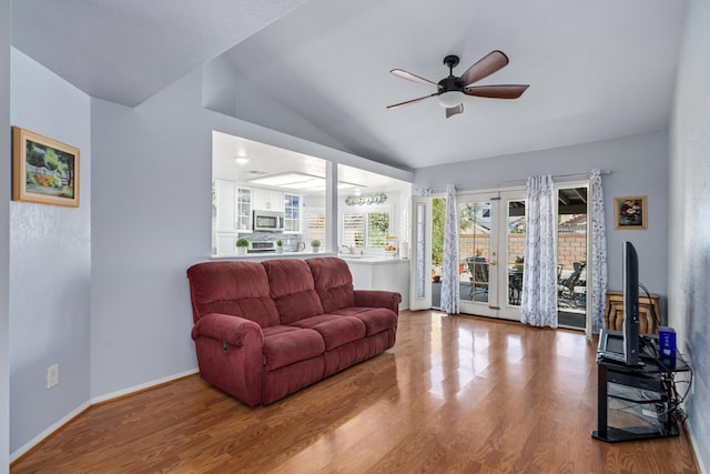 living room with ceiling fan, wood-type flooring, and vaulted ceiling