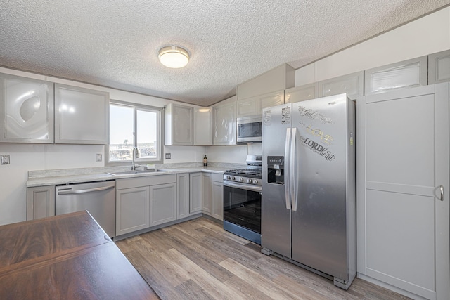 15035 E E Ave Unit G, Lancaster, CA 93535 - kitchen with stainless steel appliances, light wood finished floors, a textured ceiling, gray cabinets, and light countertops