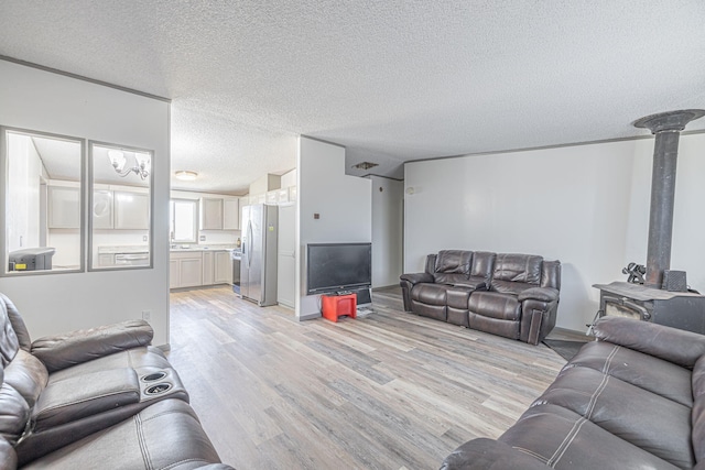 15035 E E Ave Unit G, Lancaster, CA 93535 - living room featuring light wood-style flooring, a textured ceiling, and a wood stove