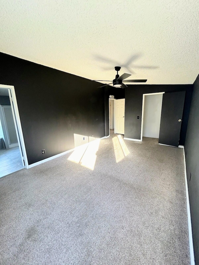 unfurnished bedroom with ceiling fan, light carpet, and a textured ceiling