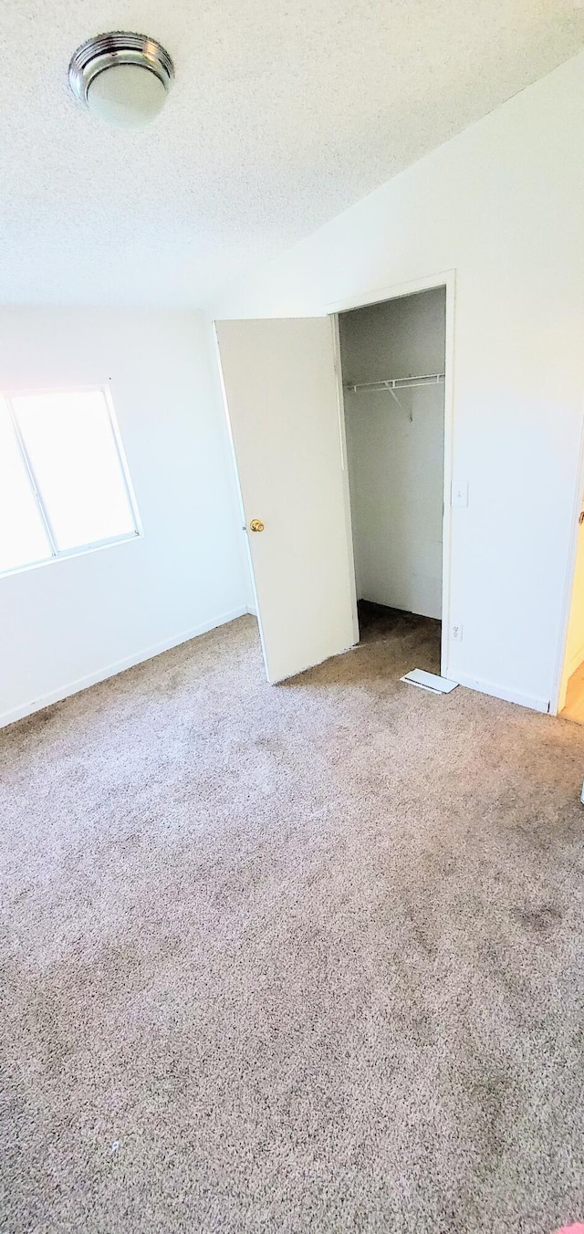 unfurnished bedroom with carpet flooring, a textured ceiling, and a closet