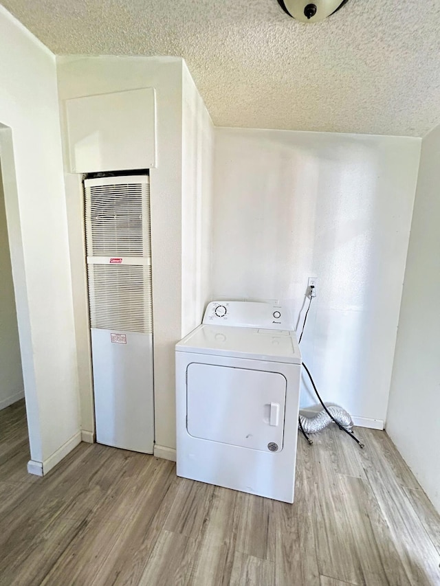 laundry room featuring a textured ceiling, light wood-type flooring, and washer / clothes dryer