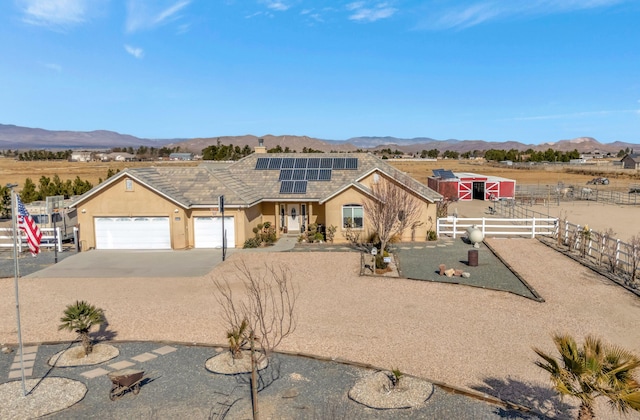 view of front of home with solar panels, a garage, and a mountain view