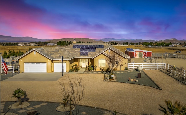 view of front facade featuring a mountain view, solar panels, and a garage