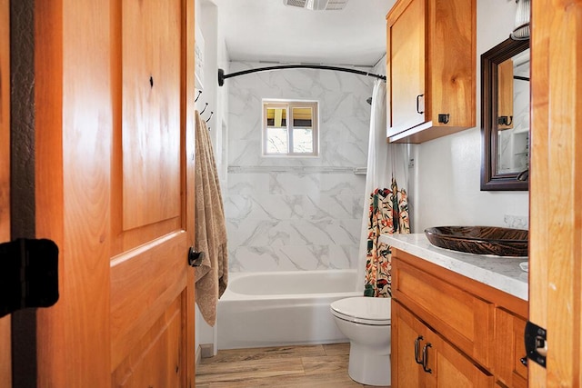 full bathroom with hardwood / wood-style flooring, vanity, shower / bath combo, and toilet