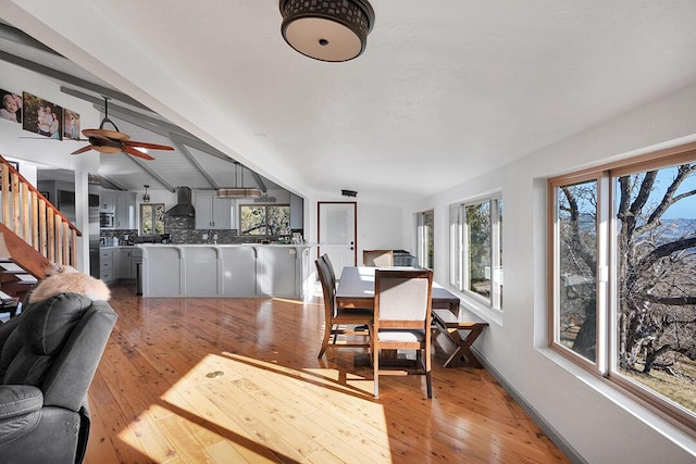 dining room with light wood-type flooring and vaulted ceiling with beams