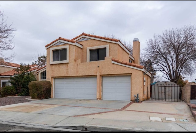 view of front facade featuring a gate, an attached garage, a chimney, stucco siding, and a tiled roof