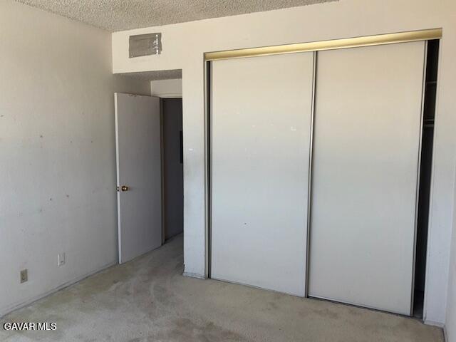 5310 Zelzah Ave Unit 305, Encino, CA 91316 - unfurnished bedroom with light carpet, a closet, and a textured ceiling