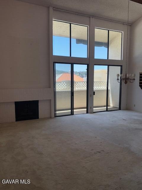 5310 Zelzah Ave Unit 305, Encino, CA 91316 - unfurnished living room with plenty of natural light, carpet floors, a fireplace, and a high ceiling