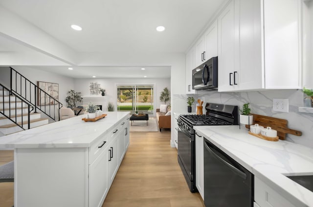 kitchen with stainless steel dishwasher, light stone counters, black range with gas stovetop, and white cabinets