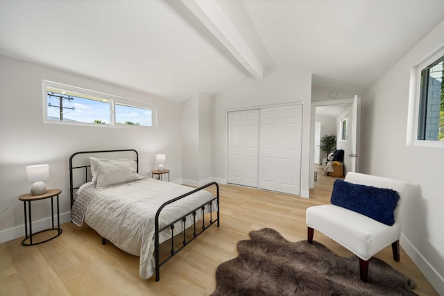 bedroom with a closet, lofted ceiling with beams, and light wood-type flooring