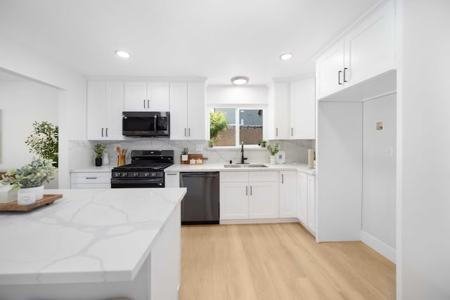 kitchen with sink, stainless steel appliances, tasteful backsplash, light stone counters, and white cabinets