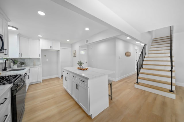 kitchen featuring a center island, white cabinetry, sink, and gas stove