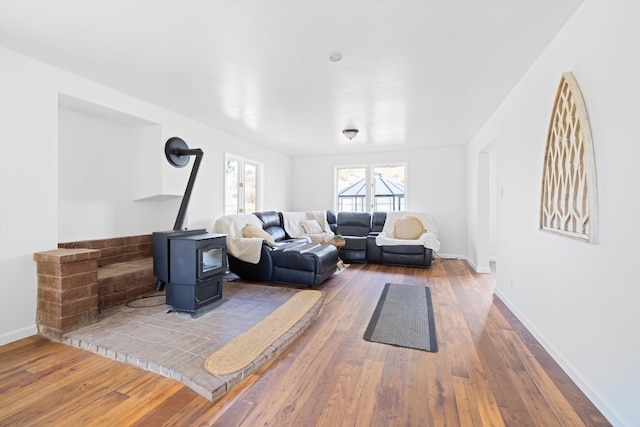 living room featuring a wood stove, hardwood / wood-style flooring, and baseboards