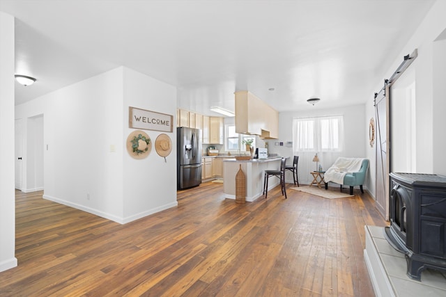 kitchen with stainless steel fridge, open floor plan, dark wood finished floors, and a peninsula