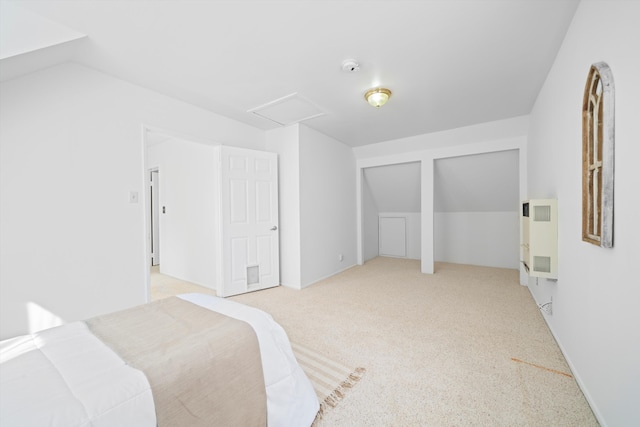 unfurnished bedroom featuring vaulted ceiling, two closets, attic access, and light colored carpet