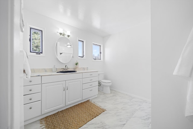 bathroom with marble finish floors, healthy amount of natural light, toilet, and vanity