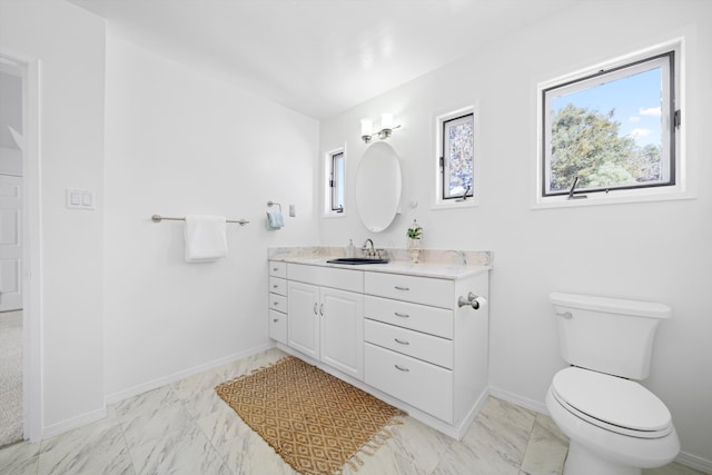 bathroom featuring toilet, vanity, baseboards, and marble finish floors