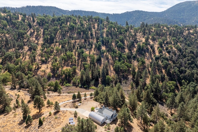 view of subject property with a heavily wooded area and a mountain backdrop